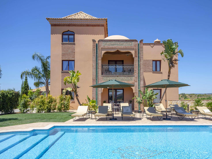 Exterior view of Al Karob Boutique Hotel with pool and sun loungers in Algarve, Portugal