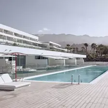 Domes Baobab Suites in Tenerife with modern architecture, a serene outdoor pool, and mountain views in the background