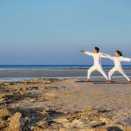 Guests doing yoga on the beach at Zulal Wellness Resort