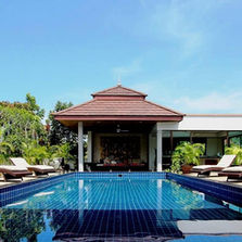 Tranquil outdoor pool with tropical plants, sun loungers, and a traditional Thai pavilion at Phuket Cleanse, Thailand.