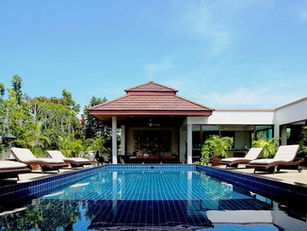 Tranquil outdoor pool with tropical plants, sun loungers, and a traditional Thai pavilion at Phuket Cleanse, Thailand.