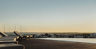 Rooftop infinity pool with lounge chairs and sunset views over the Algarve coast