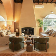 Lounge at Shanti-Som Algarve, with a sculptural fireplace and arched windows onto the garden