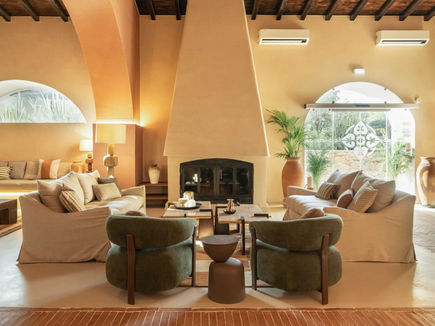 Lounge at Shanti-Som Algarve, with a sculptural fireplace and arched windows onto the garden