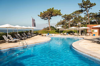 Outdoor swimming pool with sun loungers and parasols overlooking the Atlantic Ocean.
