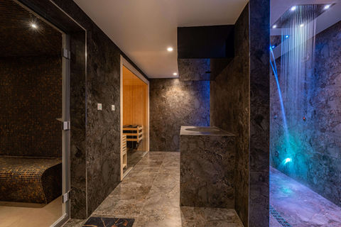Spa corridor with stone walls, ambient lighting and rainfall showers.