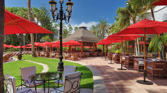 Outdoor dining terrace with red parasols at Hotel Botanico Tenerife