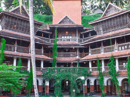 Heritage-style wooden balconies and lush gardens at Ayursoma Kerala wellness retreat.