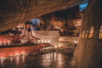 Woman meditating with candles in Arjan Cave at Kamalaya Koh Samui