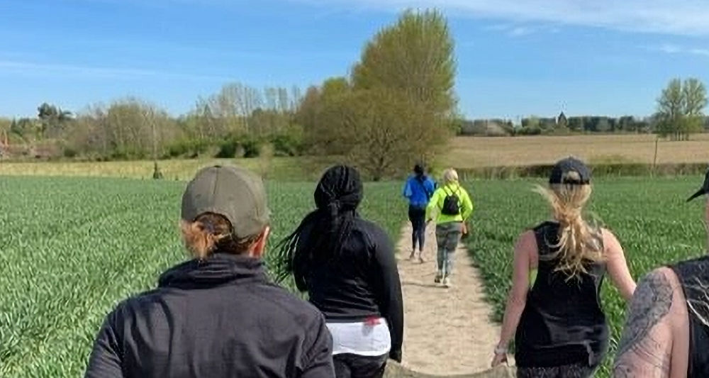 Group carrying sandbags on a countryside trail as part of GI Jane Bootcamp’s endurance training.