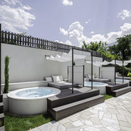 Secluded outdoor spa loungers and hot tubs with mountain views at Preidlhof wellness hotel