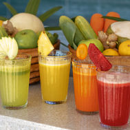 Basket of fresh fruit and vegetables beside four cold-pressed juices