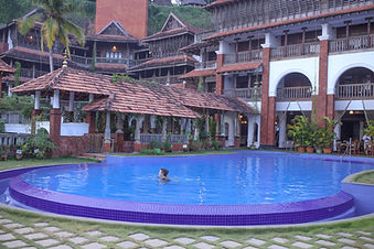 Guest swimming in the outdoor pool surrounded by Ayurvedic retreat buildings.