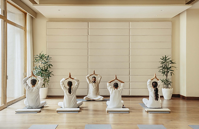 Guests practising seated yoga postures in a serene wellness studio at Six Senses Vana, India