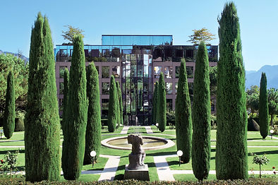 Manicured gardens with cypress trees and fountain at Clinique La Prairie Montreux