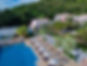 Aerial view of Absolute Sanctuary in Koh Samui, Thailand, featuring a large swimming pool surrounded by sun loungers and parasols, with tropical greenery in the background.