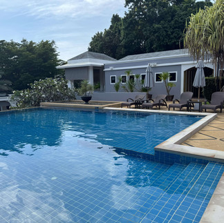 Outdoor swimming pool at Absolute Sanctuary surrounded by sun loungers and tropical plants.