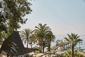 View of Marbella Club pier framed by palm trees and Mediterranean Sea