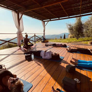 Morning yoga class under a shaded terrace with views of the Tuscan landscape at Tuscan Fitness.