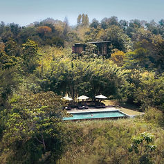 Aerial view of Santani Wellness Resort surrounded by dense forest and hillside terrain