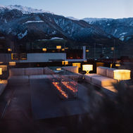 Evening view of the outdoor fireplace terrace surrounded by the Alps at Lindenhof Lifestyle DolceVita Resort.