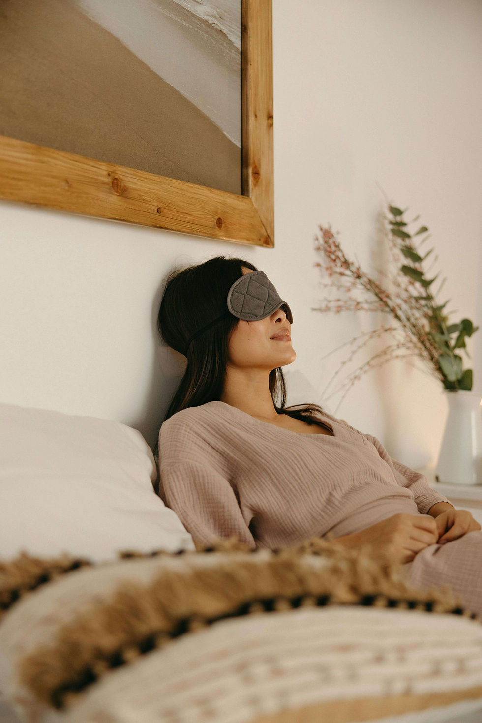 Woman relaxing in bed with an eye mask during a sleep enhancement retreat