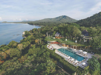 Aerial view of Kamalaya Wellness Sanctuary in Thailand, surrounded by lush tropical greenery, a sparkling pool, and the stunning coastline.
