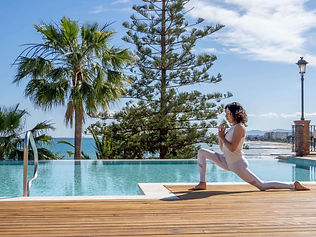 Woman practising yoga by infinity pool with sea views at Palasiet Wellness Retreat