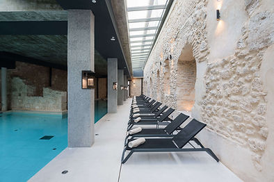 Spa relaxation loungers by stone wall at Castilla Termal Brihuega