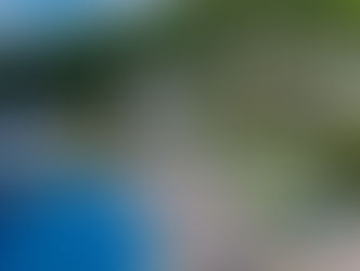 Aerial view of Absolute Sanctuary in Koh Samui, Thailand, featuring a large swimming pool surrounded by sun loungers and parasols, with tropical greenery in the background.