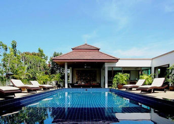 Tranquil outdoor pool with tropical plants, sun loungers, and a traditional Thai pavilion at Phuket Cleanse, Thailand.