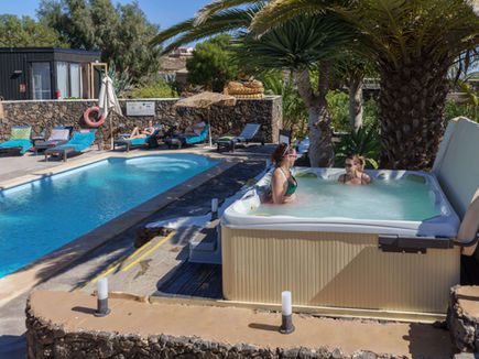 Guests relaxing in the outdoor hot tub beside the pool at Azulfit Wellness Retreat, Spain