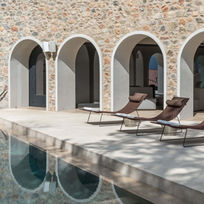 Tranquil thermal pool with arched stone facade and loungers at Euphoria Retreat in Greece