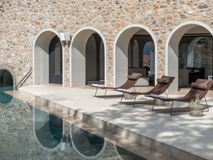 Tranquil thermal pool with arched stone facade and loungers at Euphoria Retreat in Greece