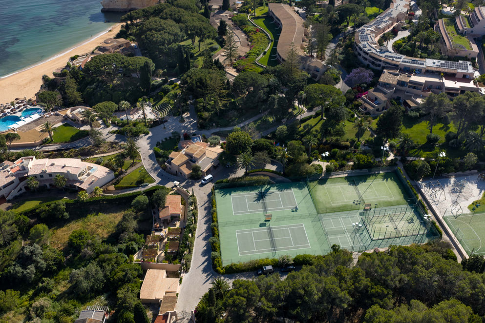 Aerial view of Vilalara Grand Hotel Algarve showing tennis courts, gardens and coastline.