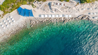 Drone view of the rocky Adriatic coastline and turquoise sea by Sun Gardens Dubrovnik resort in Croatia.