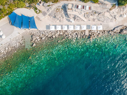 Drone view of the rocky Adriatic coastline and turquoise sea beside Sun Gardens Dubrovnik.