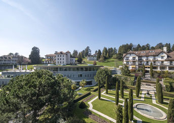 Elegant lakeside setting of Clinique La Prairie in Montreux, Switzerland, featuring a grand white building surrounded by manicured gardens with views over Lake Geneva