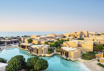 Lagoon-style pool surrounded by palm trees in Qatar, ideal for stress relief and relaxation wellbeing escapes.