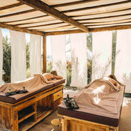 Open-air massage cabana with twin treatment tables and linen curtains at Paradis Plage