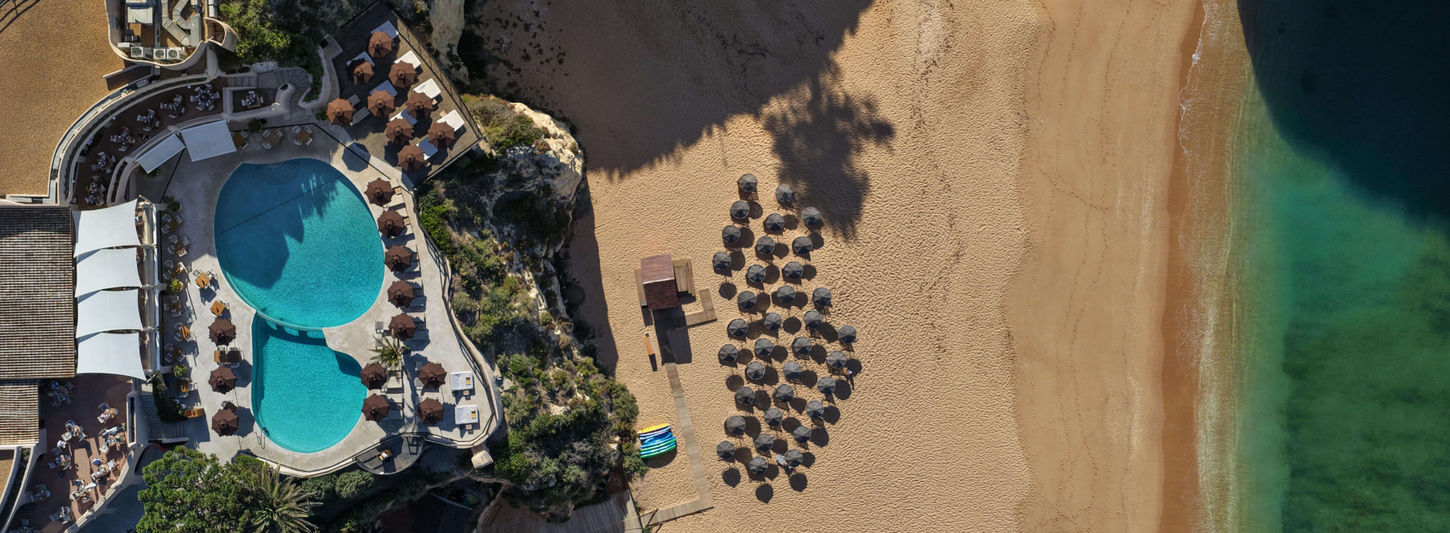 Bird’s-eye view of the beachfront pool and sandy cove at Vilalara Grand Hotel Algarve.