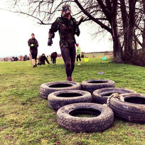 Women exercising on a grassy field during a bootcamp session involving tyre drills at GI Jane Bootcamp UK.