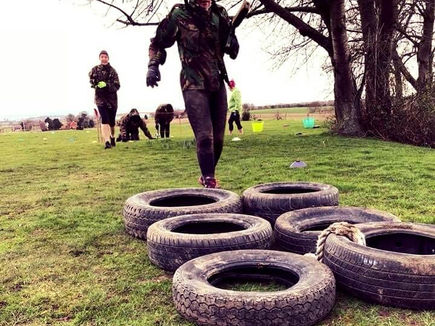 Women completing a tyre obstacle workout outdoors at GI Jane Bootcamp in England.