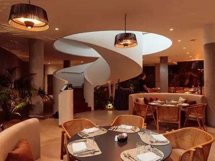 Restaurant interior at Domes Baobab Suites, with a sculptural spiral staircase