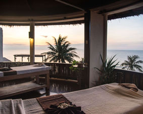 Tropical spa setting with massage beds and ocean view.