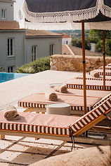 Rolled towels on striped sun loungers by the outdoor pool at Shanti-Som Algarve