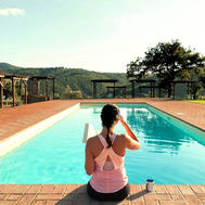 Guest reading a book beside the pool at Tuscan Fitness wellness retreat in the Italian countryside.