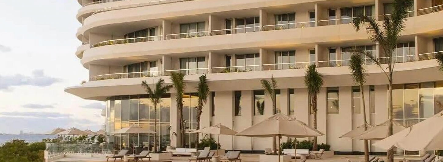 Modern beachfront resort with palm trees and poolside loungers at SHA Wellness Clinic Mexico