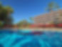 Hotel Botanico & The Oriental Spa Garden in Tenerife, featuring a serene swimming pool surrounded by palm trees and sun loungers with red umbrellas