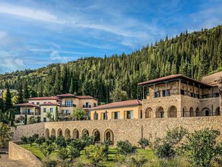 Stone-built Euphoria Retreat in the Peloponnese, Greece, nestled against a forested hillside with elegant architecture and Mediterranean gardens